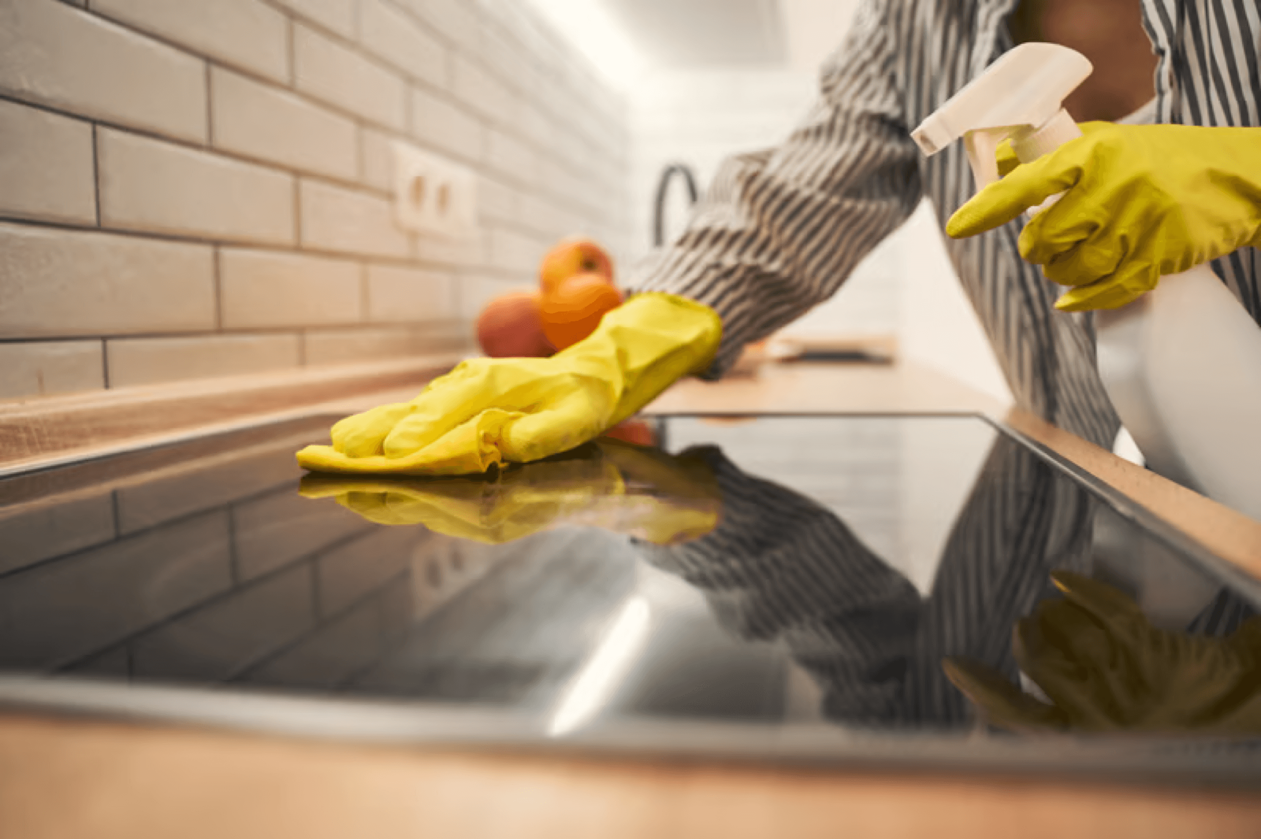 Close-up of a gloved hand deep cleaning a kitchen cooktop
