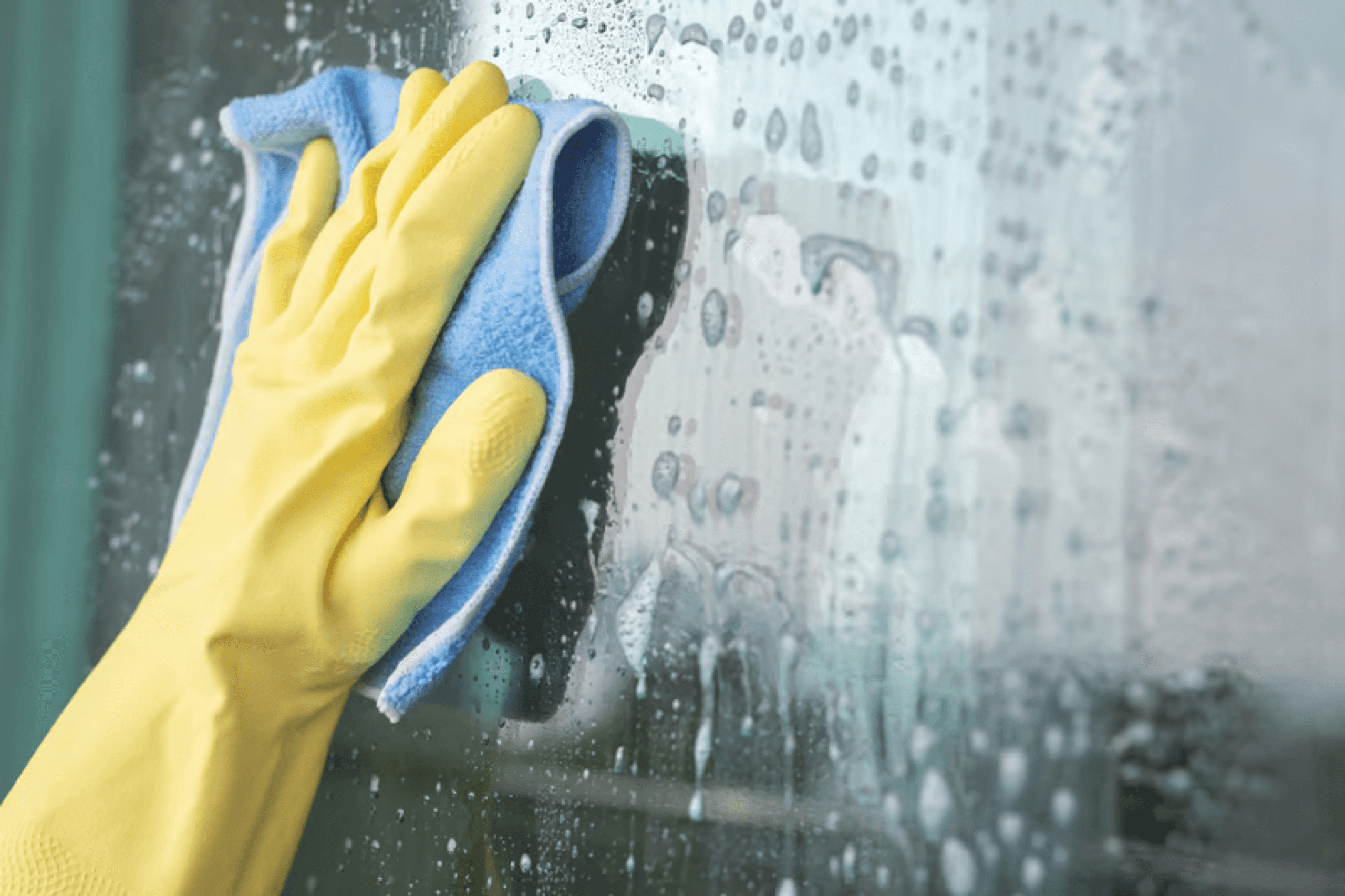Gloved hand wiping a window until the glass shines