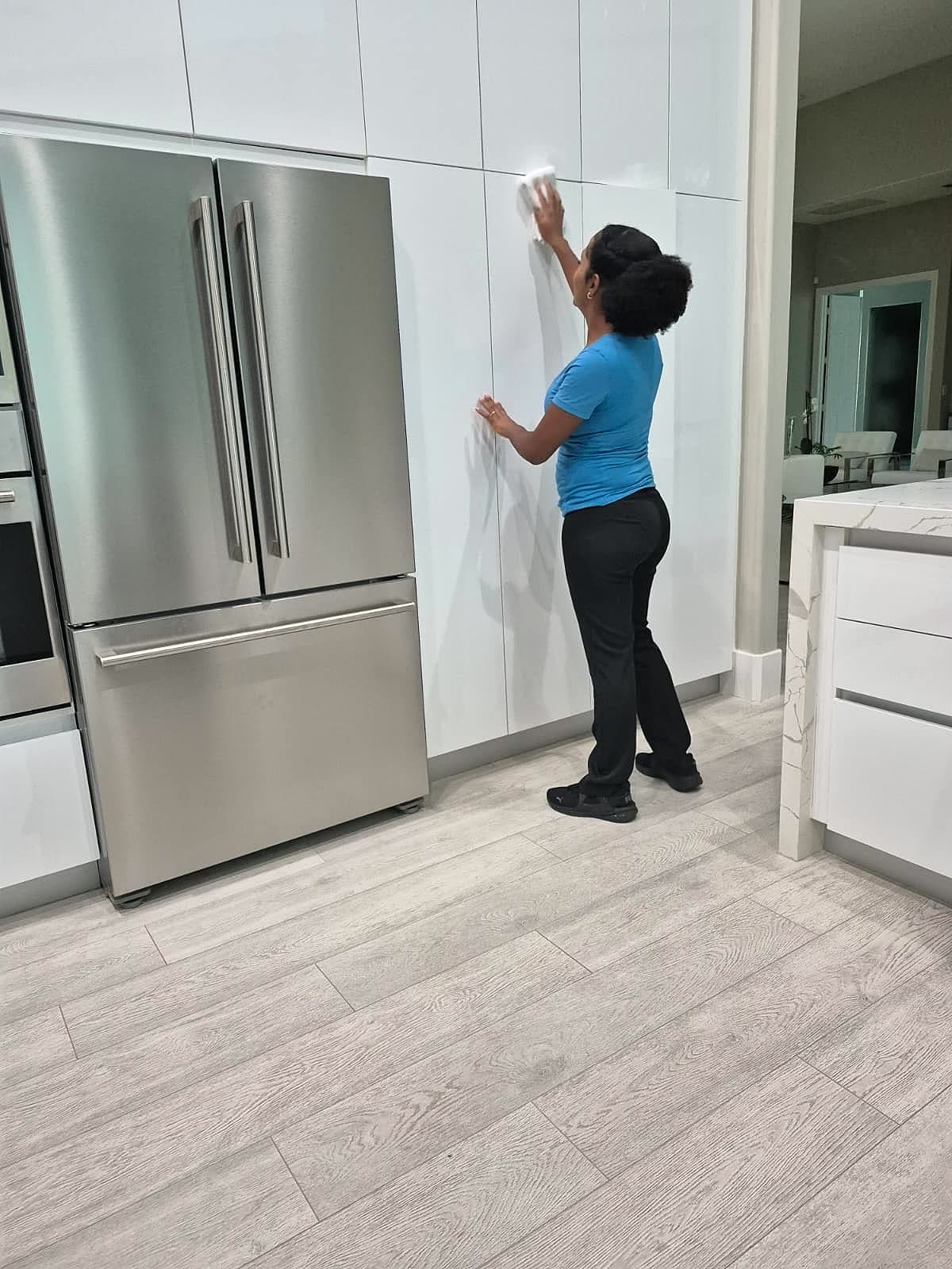 Alessandra wiping high-gloss kitchen cabinets in a modern home