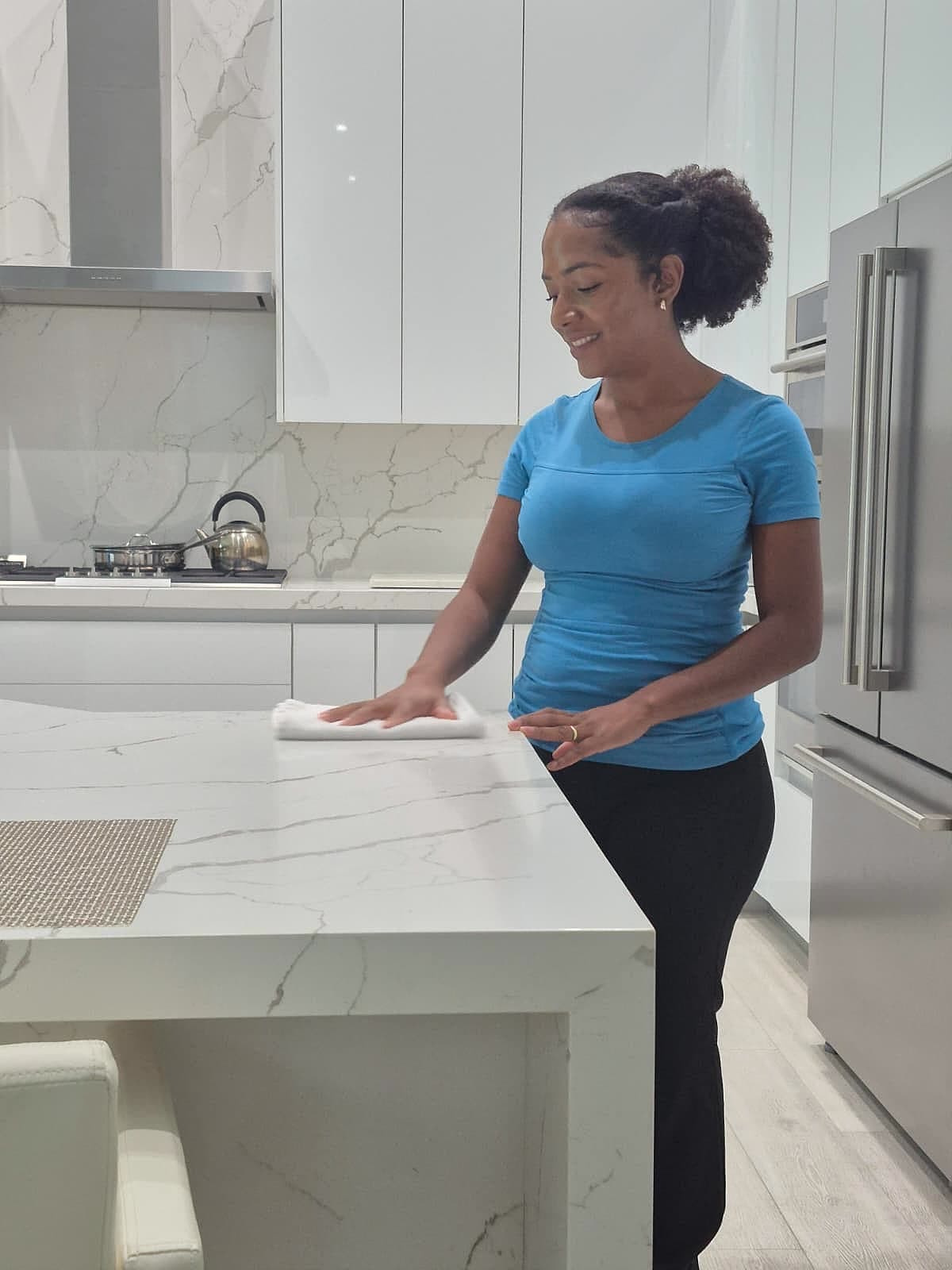 Alessandra wiping down a marble kitchen island in a Delray Beach home