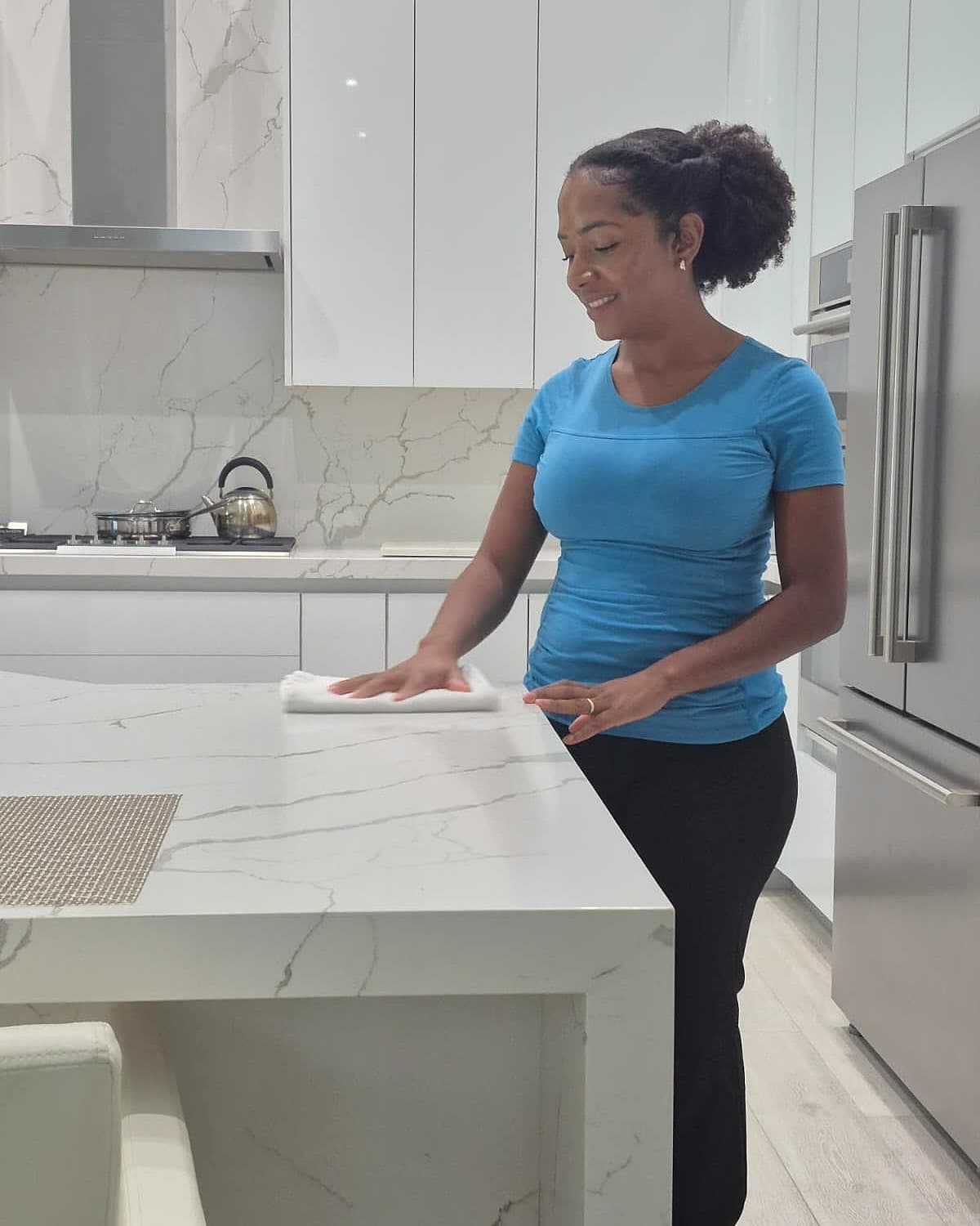 Alessandra, owner of A&D Cleaning Services, cleaning a marble kitchen counter in Delray Beach